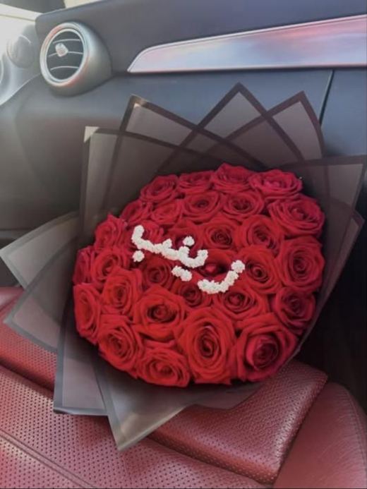 Dome of red roses in black wrap with a name written in Arabic in gypsophila