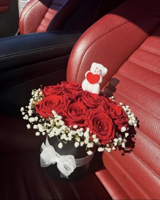 Red roses and gypsophila in a black hat box with a white bow and a small teddy