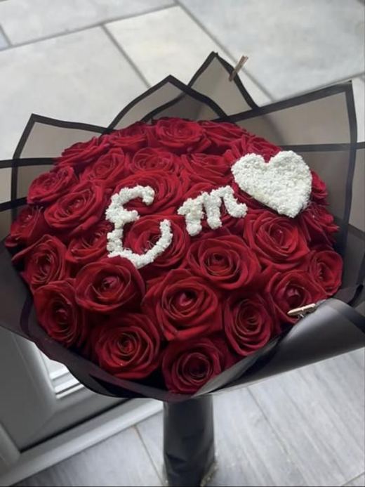 Red rose bouquet in black wrap with initials and a heart in gypsophila